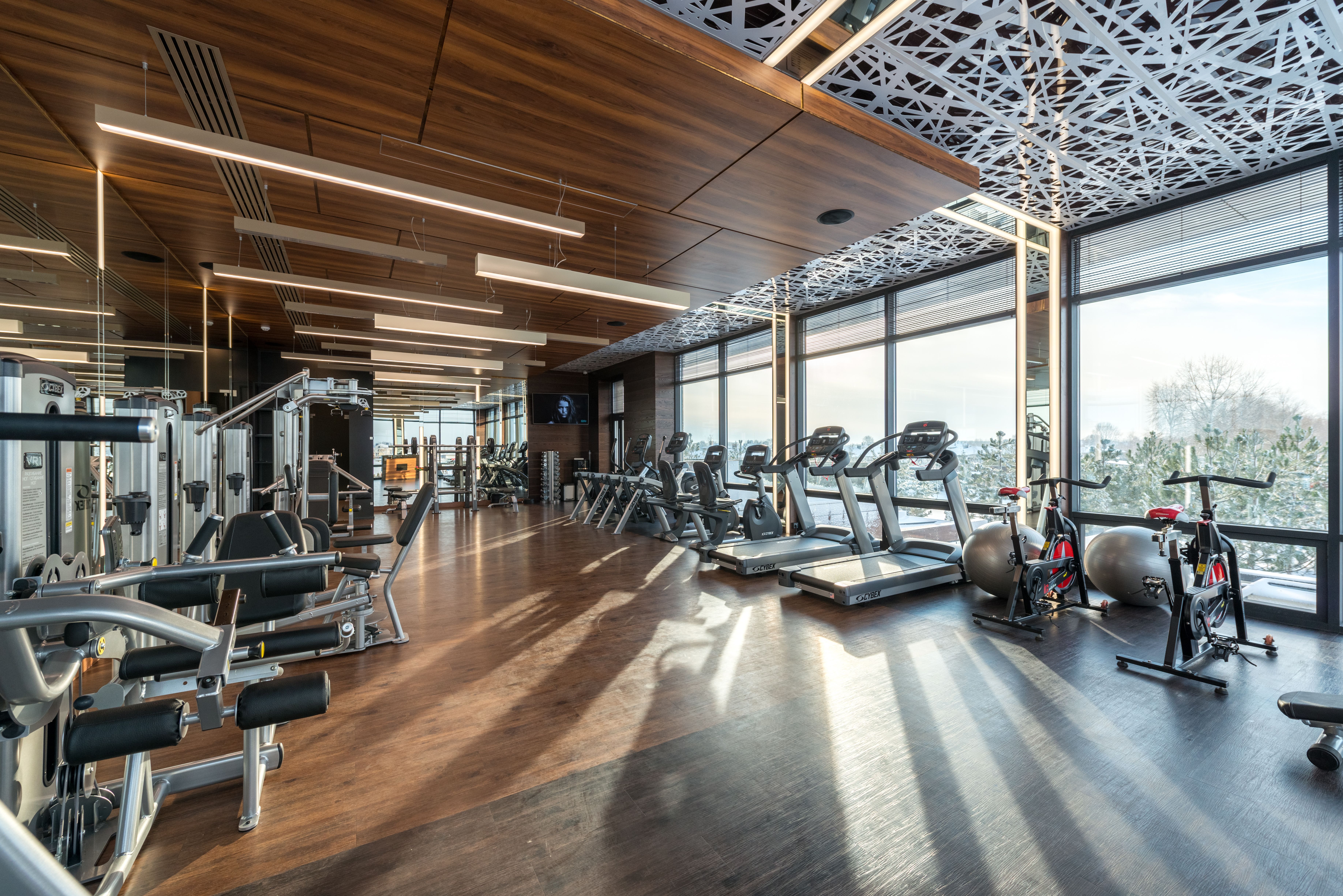 An empty gym floor in early morning light, weights racked, nobody there
