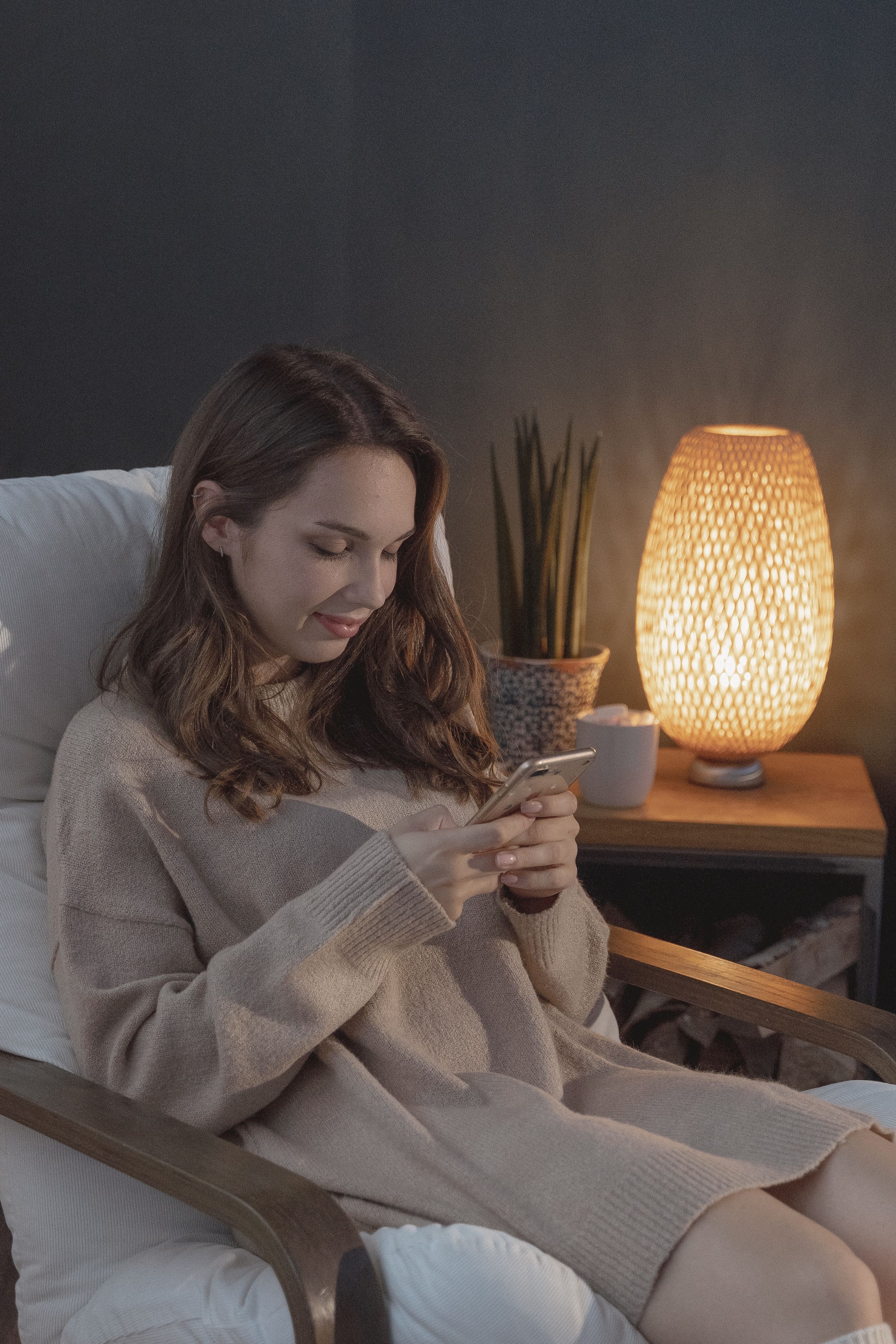 A quiet living room in the evening, lamp on, phone on the arm of a chair
